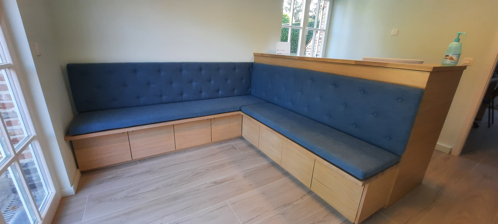 Grande banquette d'angle capitonnée en tissu bleu, structure en chêne clair sur mesure