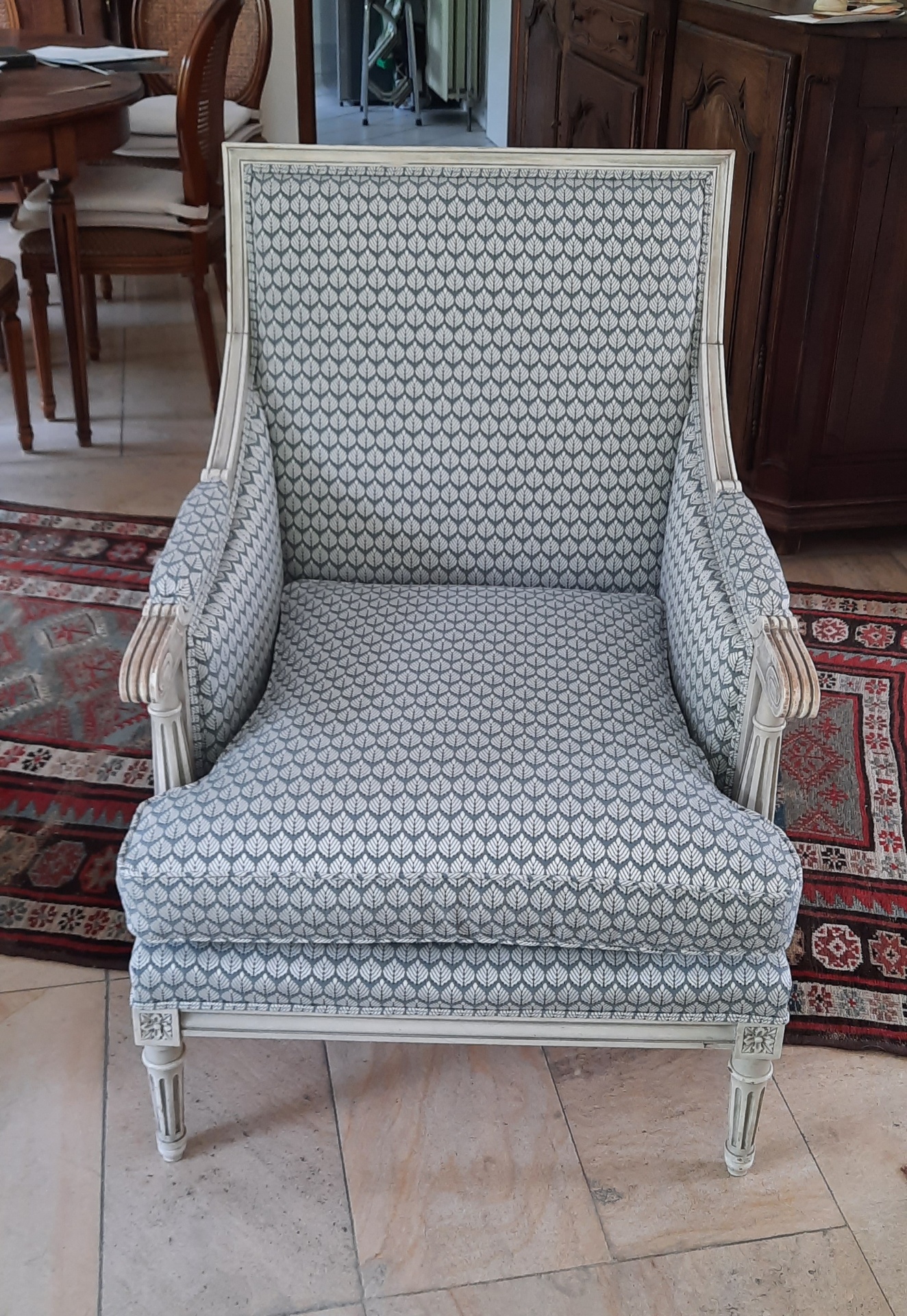 Bergère Louis XVI garnie en tissu motif feuilles bleu-gris, bois patiné blanc