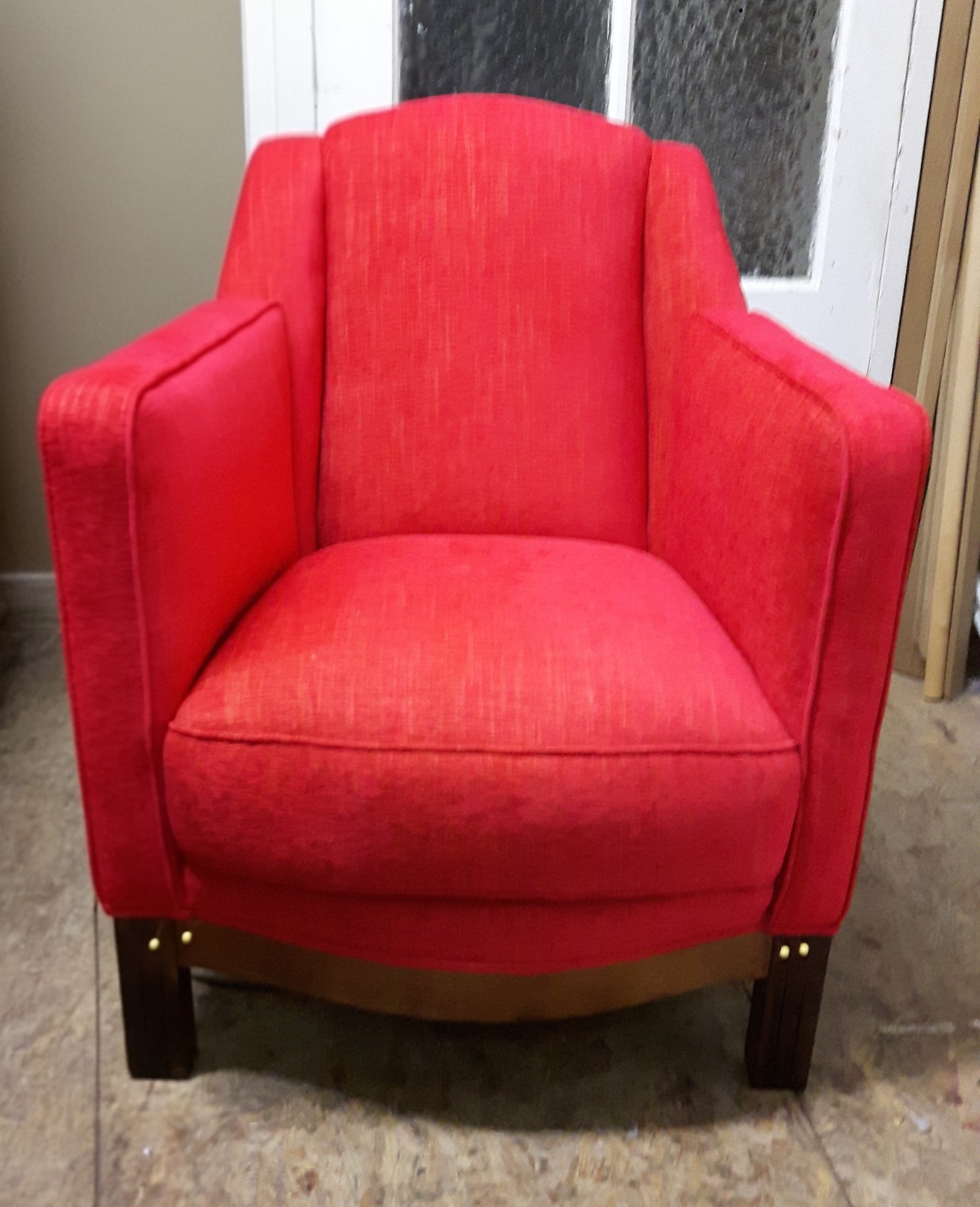 Fauteuil club Art déco garni en tissu rouge vif, base bois acajou cloutée laiton